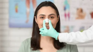 How long do rhinoplasty results last — woman with bandage after nose reshaping surgery